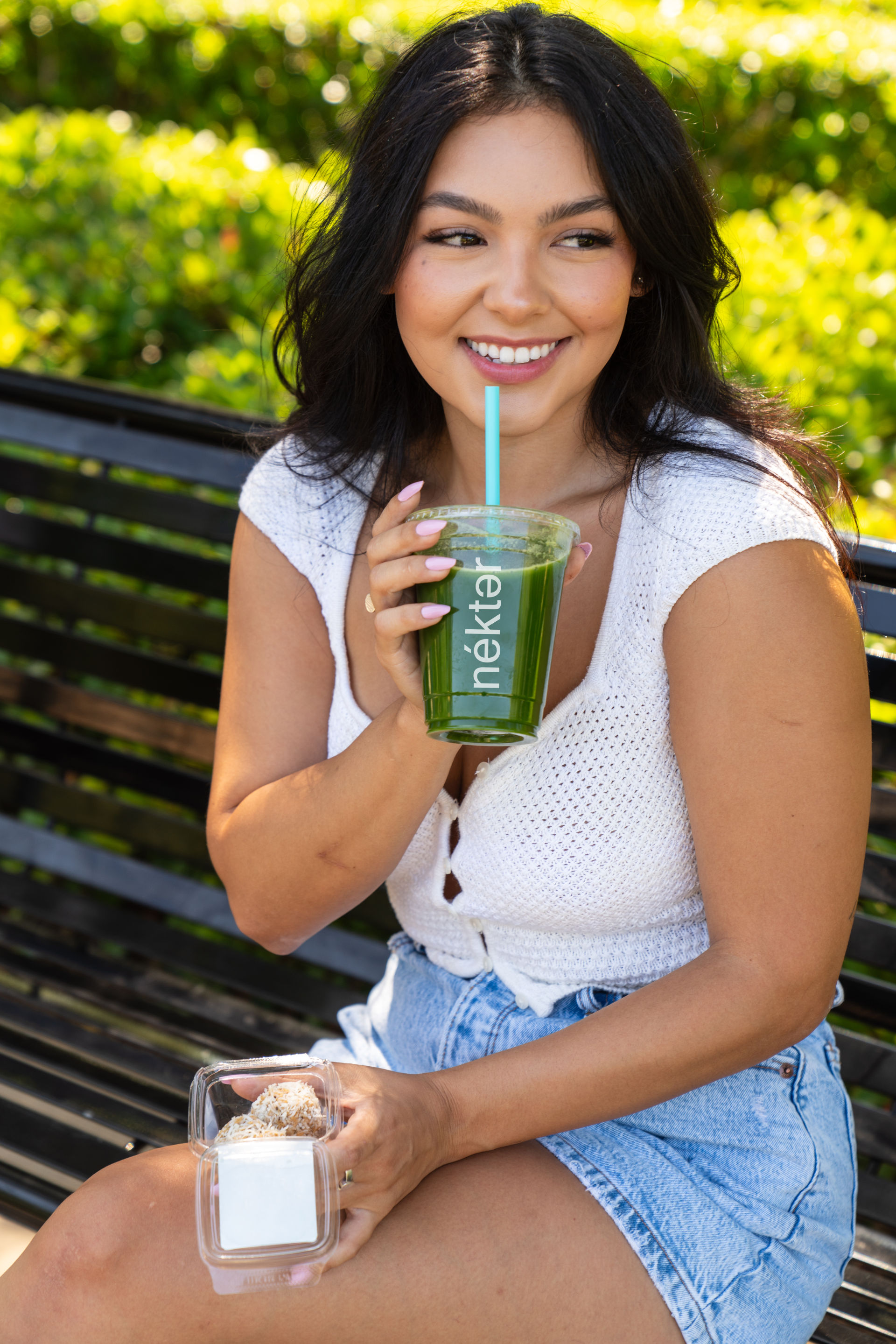 Smiling woman sipping juice and holding protein poppers