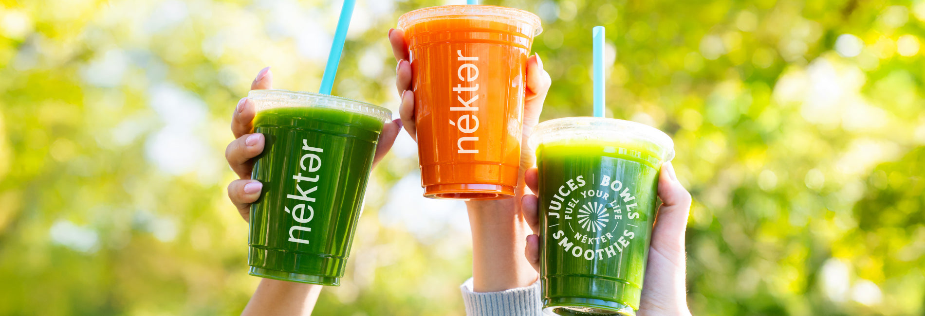 2 Green juices and a carrot juice with trees in the background
