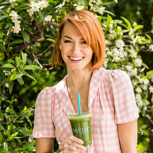 Smiling woman with green juice from nekter juice bar