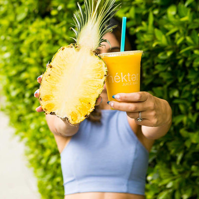 Woman holding pineapple and smoothie