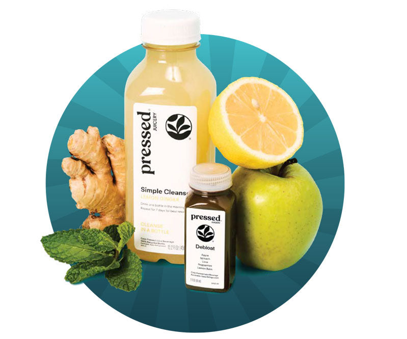 Two bottles of 'pressed' juice with a lemon, apple, and ginger on a blue circular background