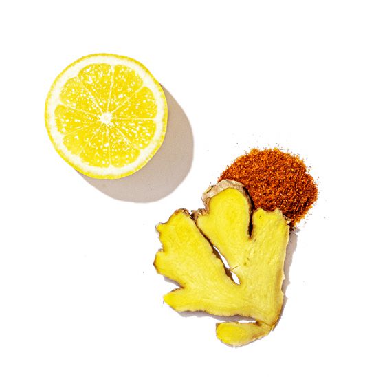 Sliced lemon and ginger root with a sprinkle of red pepper on a white background
