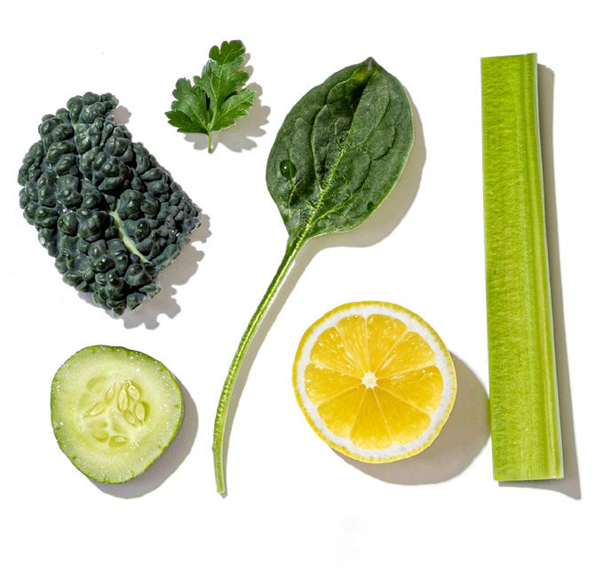 Collection of green vegetables and a lemon on a white background