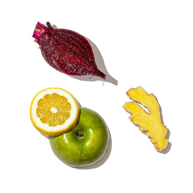 Fruits and vegetables including a lemon, apple, beetroot, and ginger on a white background