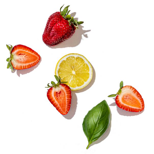 Strawberries, lemon, and basil leaves on a white background