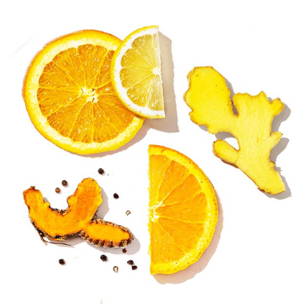 Sliced oranges, lemons, turmeric, and ginger on a white background