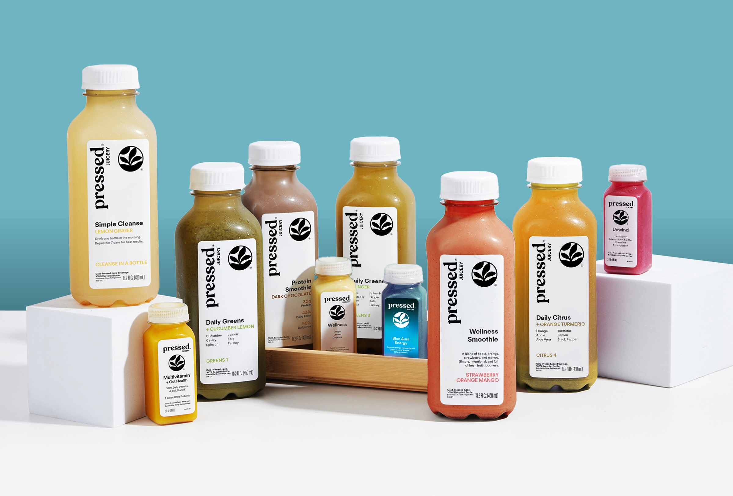 Assorted 'pressed' juice bottles on a white surface with a blue gradient background