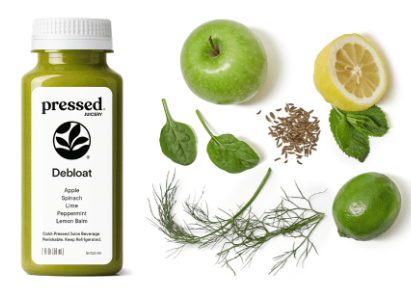 Bottle of 'pressed' debloat supplement with green apple, lemon, and herbs on a white background